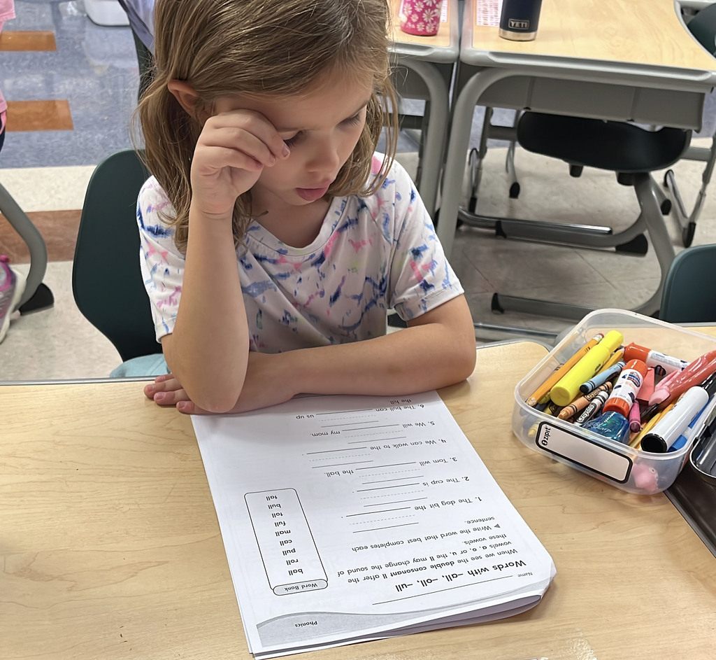 A student whose class is rotating to different language arts stations works on an assignment.