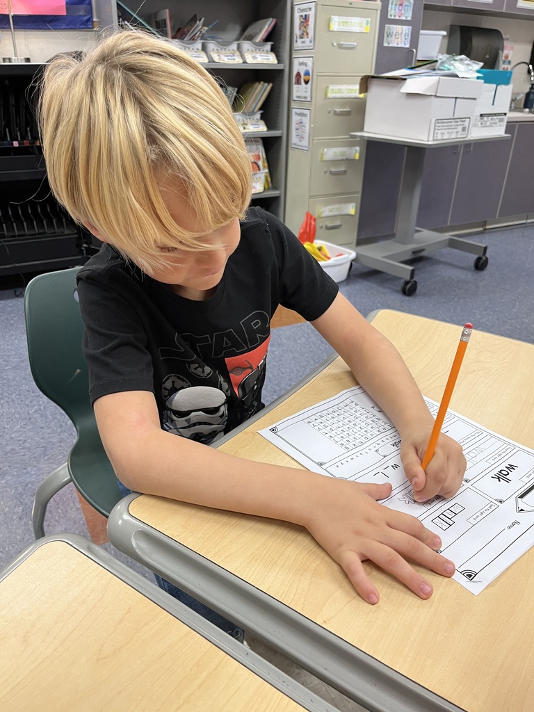 A student whose class is rotating to different language arts stations works on an assignment.