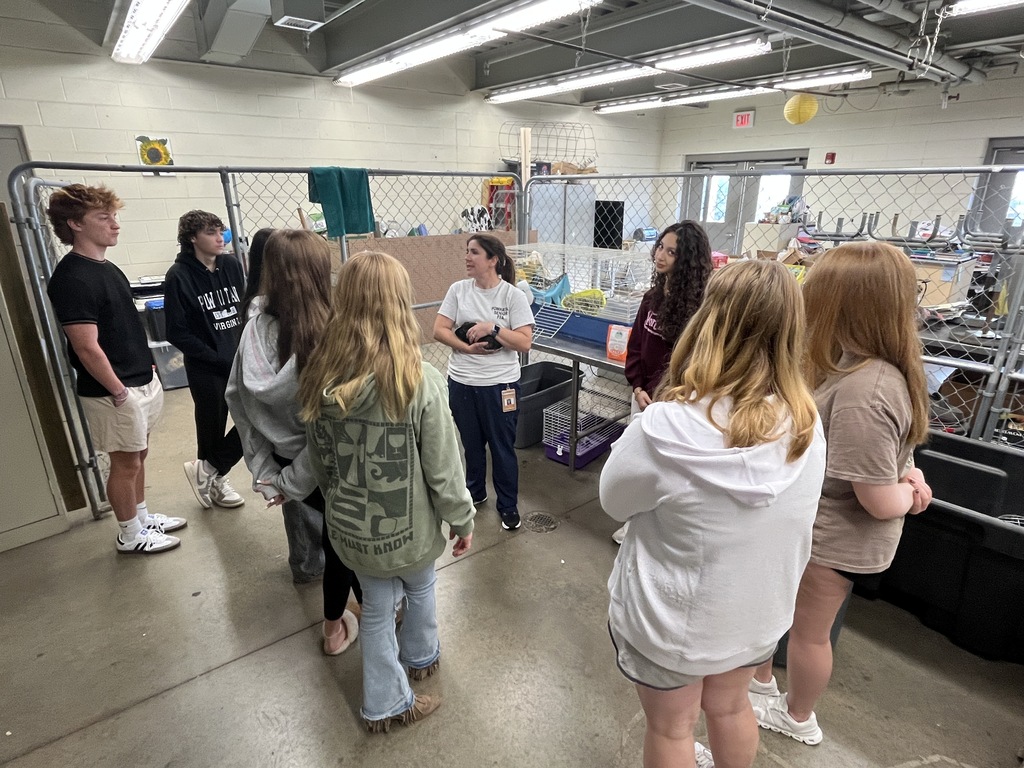 A teacher holding a guinea pig talks to her small animal care class about how to properly care for him.