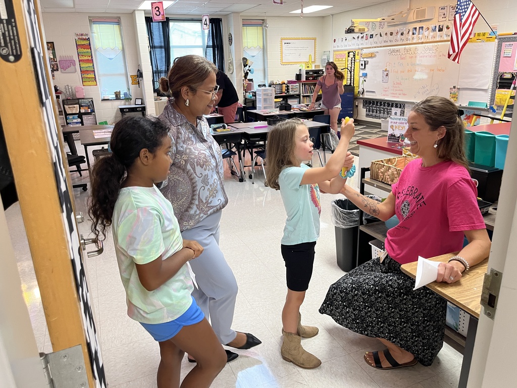 A teacher meets a new students and their families at an elementary school open house. 