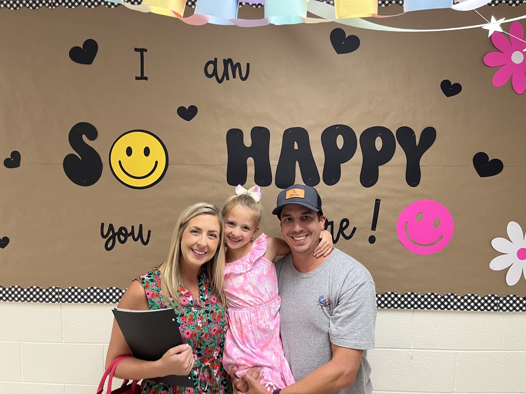 Two adults and a child pose for a photo at an elementary school open house. 