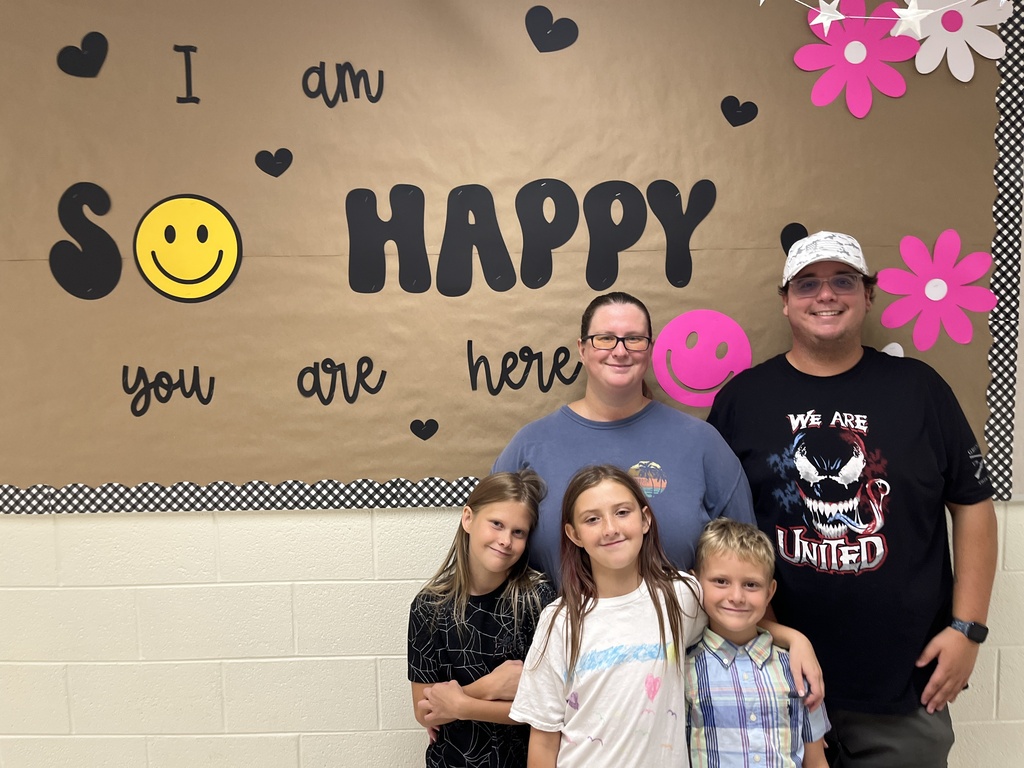 Two adults and three children pose for a photo at an elementary school open house. 