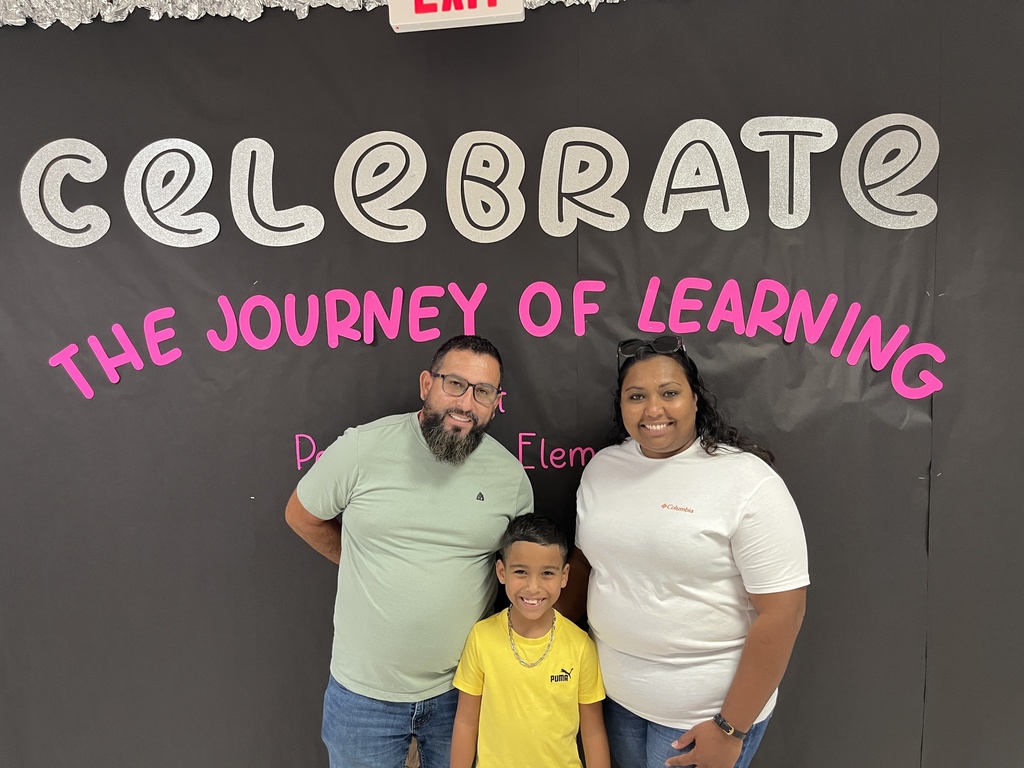 Two adults and a child  pose for a photo at an elementary school open house. 