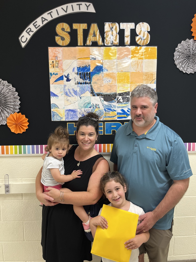 Two adults and two children pose for a photo at an elementary school open house. 
