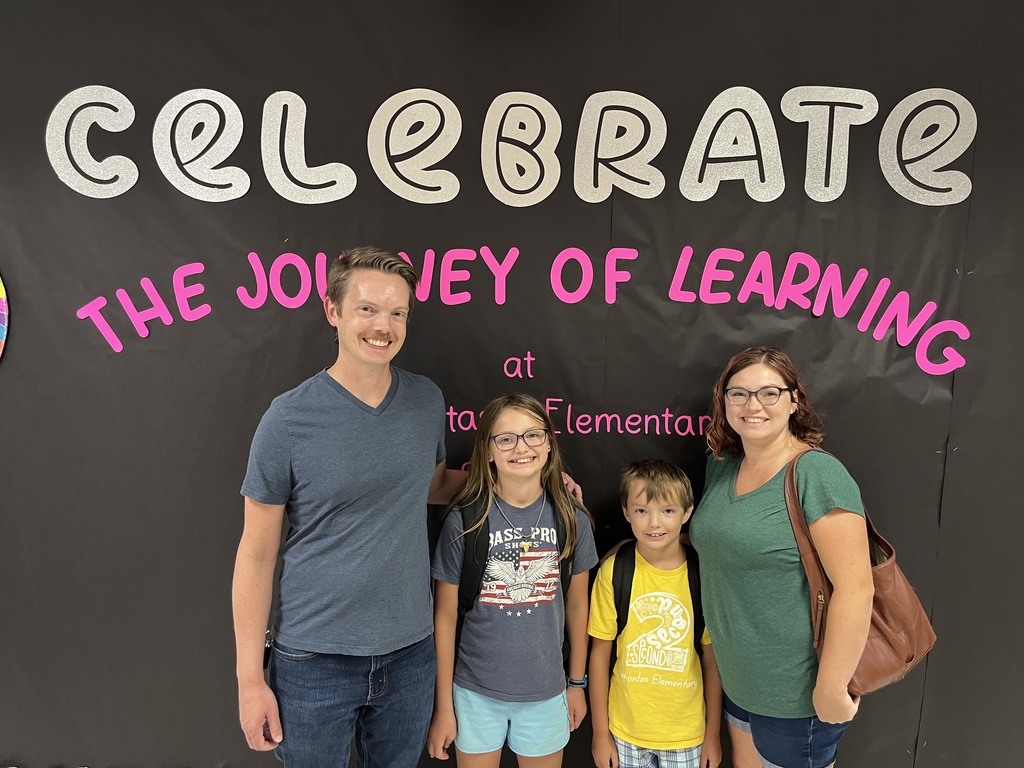 Two adults and two children pose for a photo at an elementary school open house. 