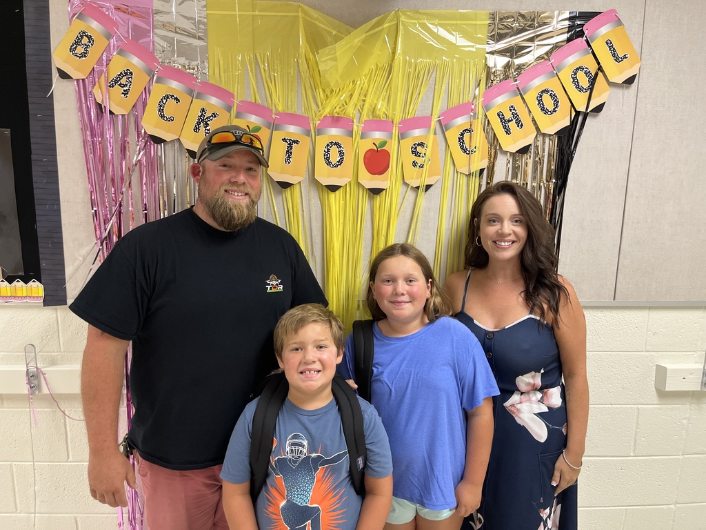 Two adults and two children pose for a photo at an elementary school open house. 