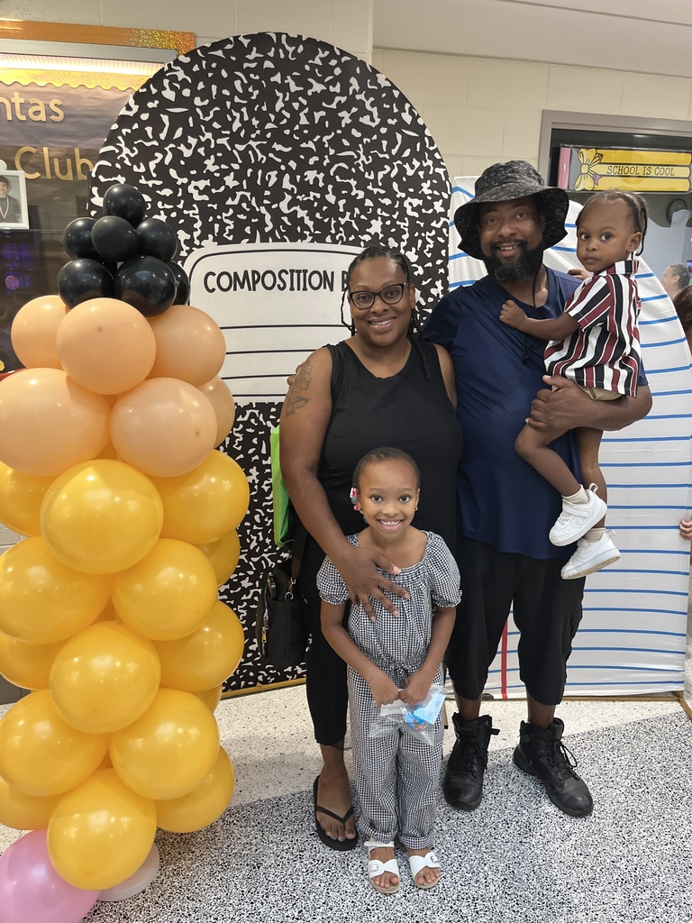 Two adults and two children pose for a photo at an elementary school open house. 