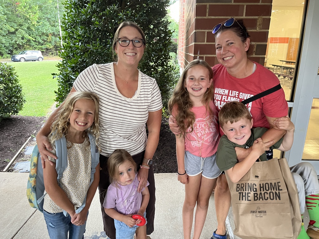 Two adults and four children pose for a photo at an elementary school open house. 