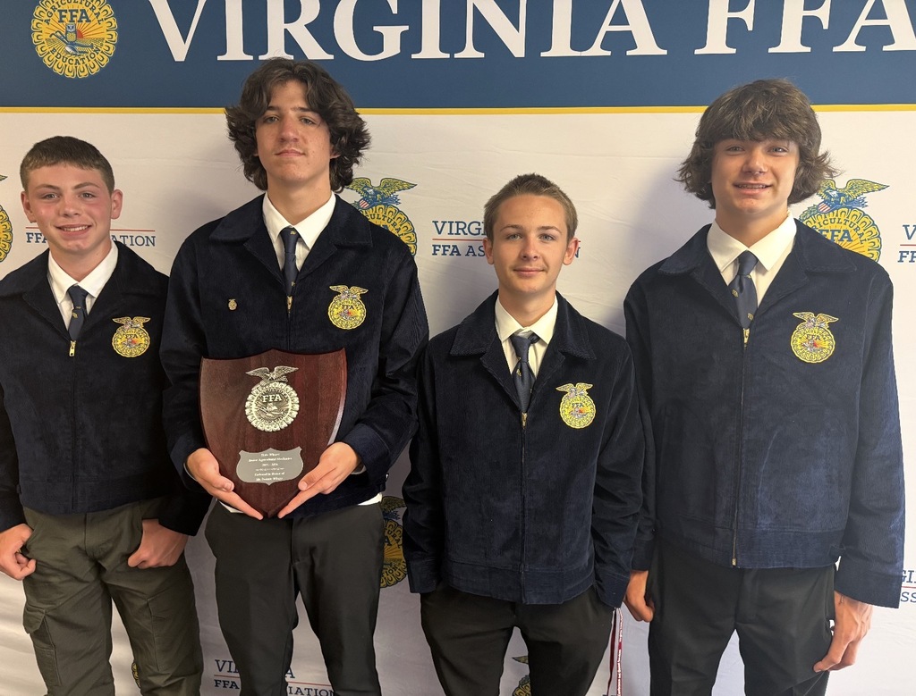 Four FFA members pose for a  photo in front of an FFA backdrop.