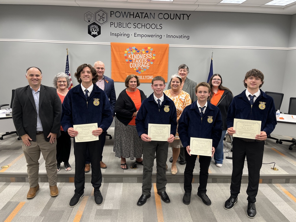 Six adults pose for a photo with five teens. Four of the teens are wearing FFA uniforms and holding certificates. 