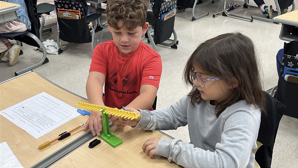 A group of students  works with a balance to help them explore equality and inequality.