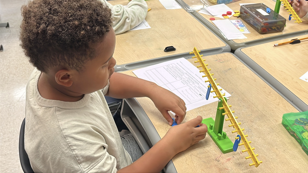 A student  works with a balance to help him explore equality and inequality.