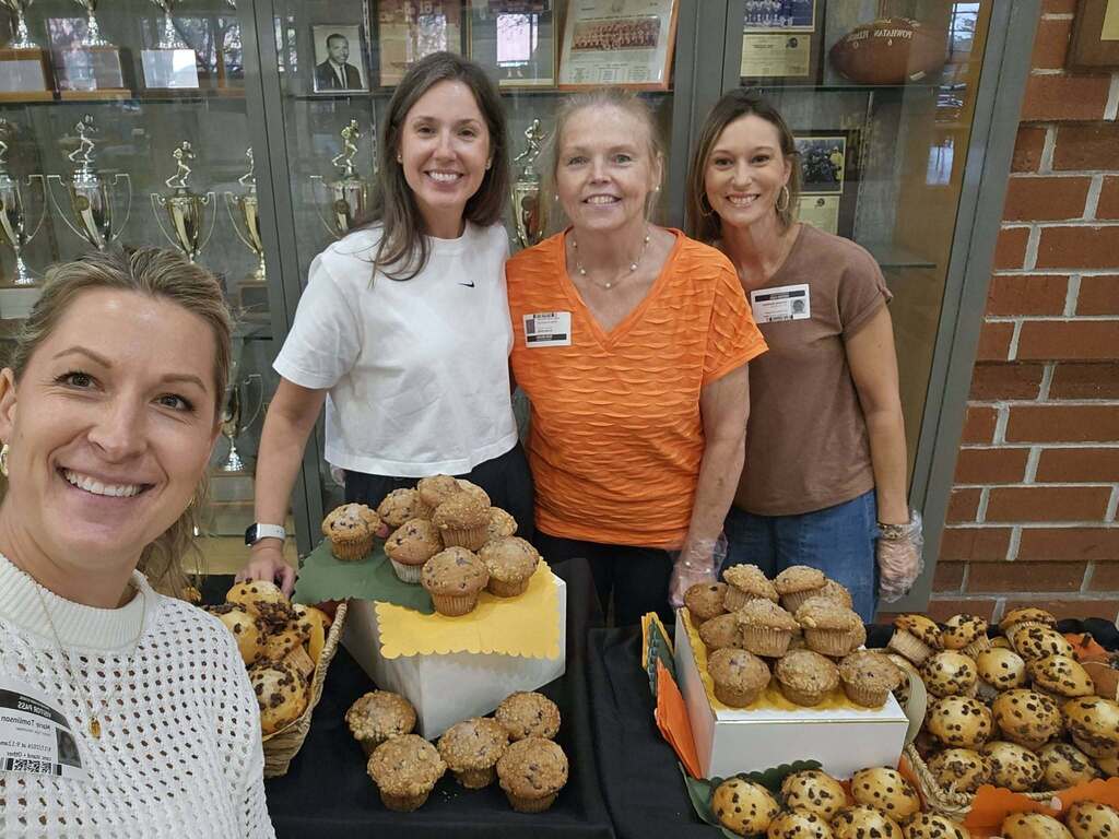 Parent volunteers pose with treats for staff members they are deliviering with a rolling cart.