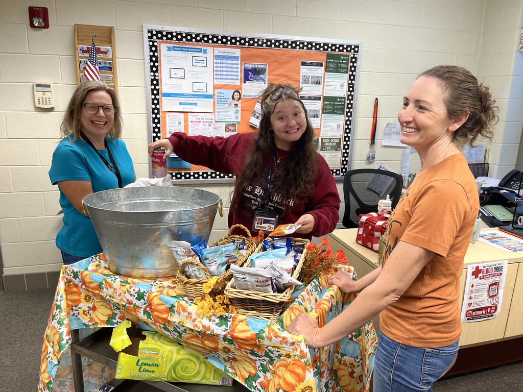Parent volunteers serve treats to a staff member with a rolling cart. 