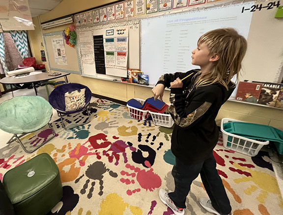 A student flies a paper airplane. 