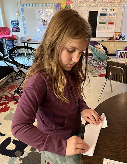 A student folds a paper airplane. 