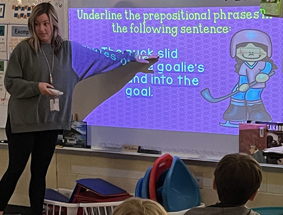 A woman teaches about prepositional phrases.
