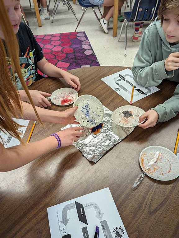Student work on an activity to model the rock cycle.
