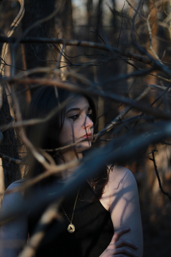 Photograph of a girl seen through thick woods.