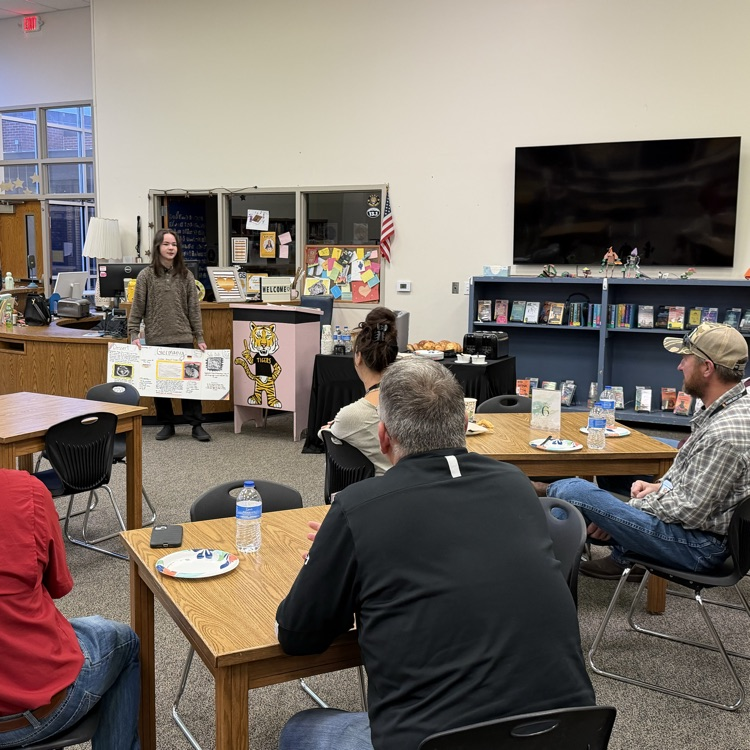 junior high students presenting their Christmas around the world poster boards to school board members