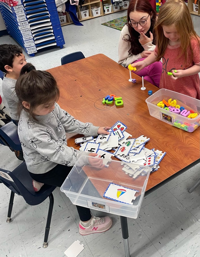 3 preschool students at a table rearranging number card and number tiles