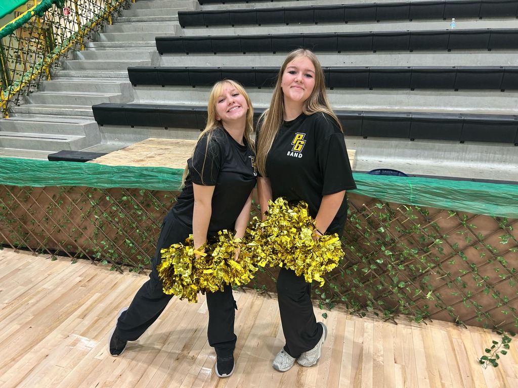 2 female color guard members holding gold pom poms and smiling together 