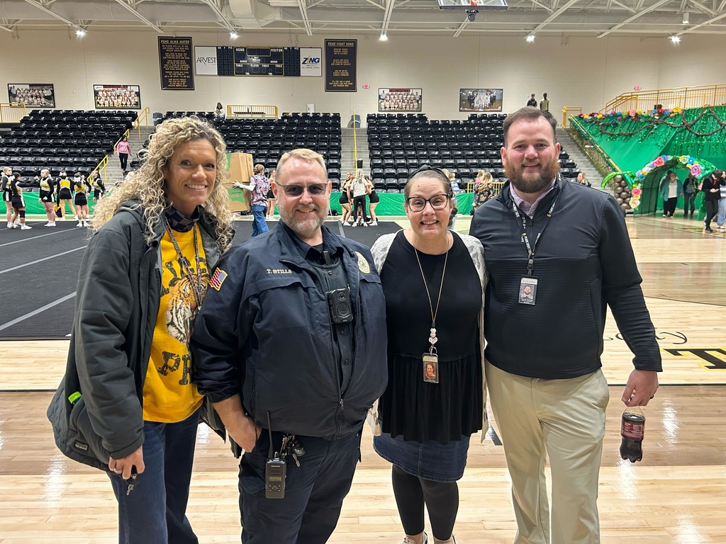 4 faculty members smiling together in the Tiger arena before the pep rally 