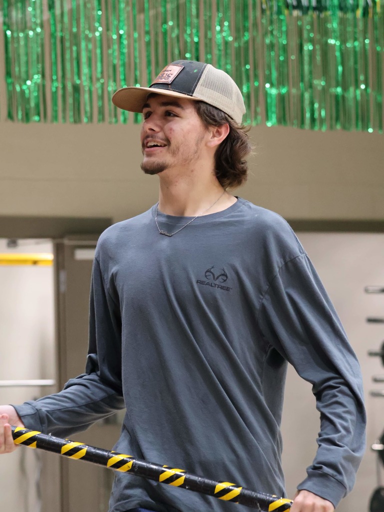 High school male in a ball cap smiling at the crowd holding the Tiger spirit stick