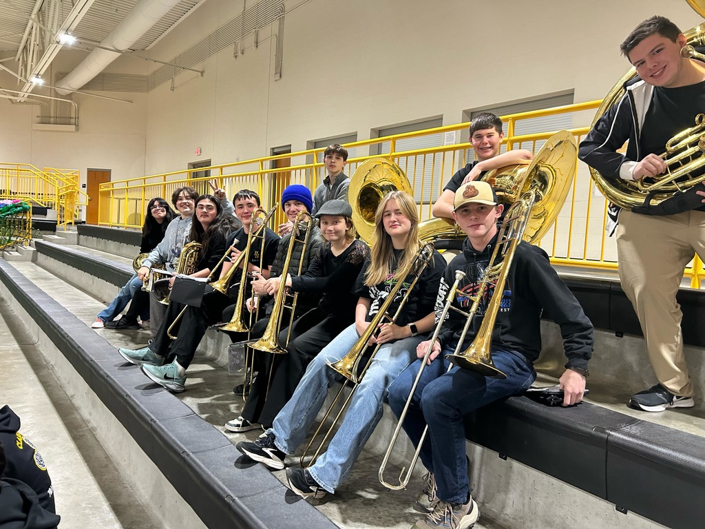 High School students holding their trombones and smiling at the camera