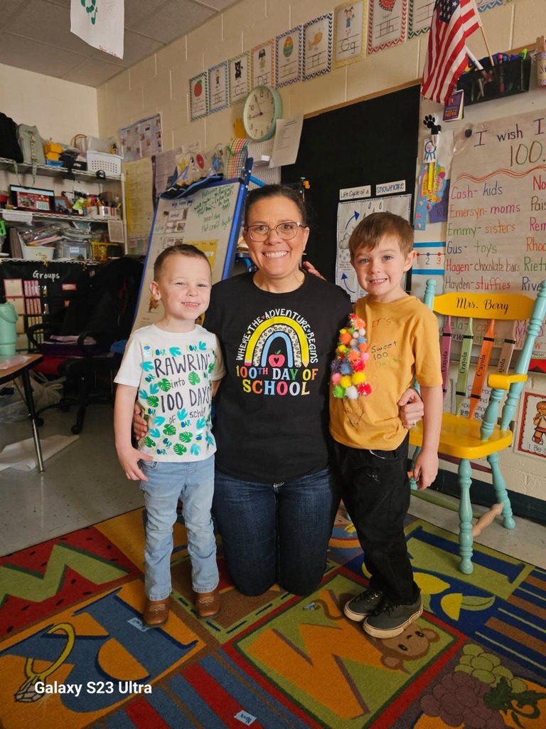 Preschool teacher with two male students showing off their 100th day of school tshirts 