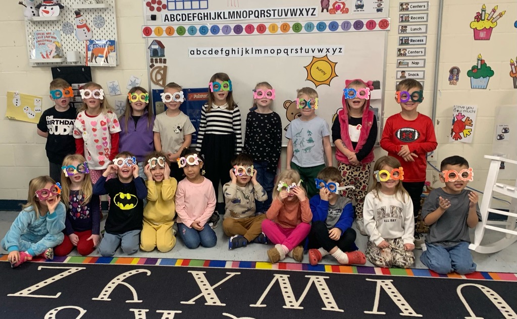 preschool class smiling together with their 100 glasses 