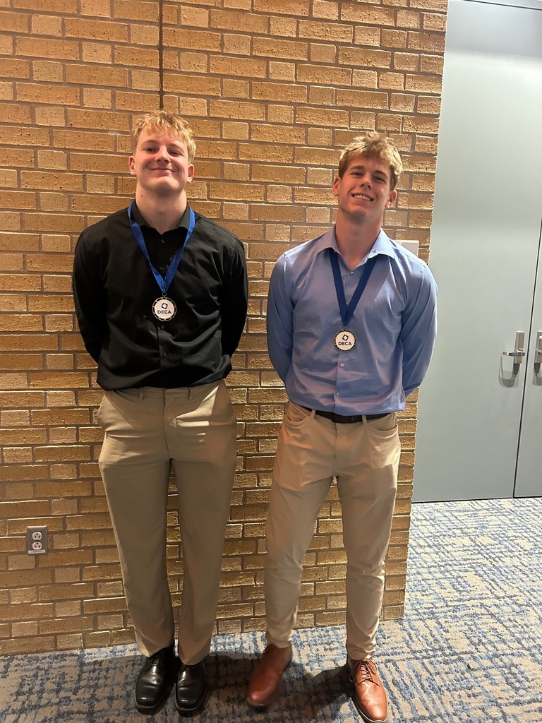 two high school boys smiling with their DECA medals