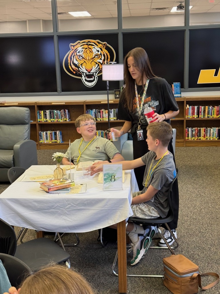 Mrs. Aboytes hands out water to students during a book tasting in the library.