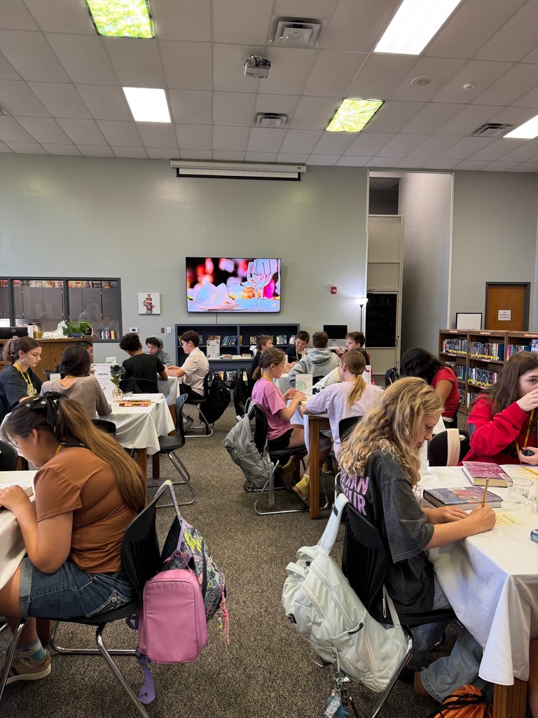 Students in the library browse books at tables.