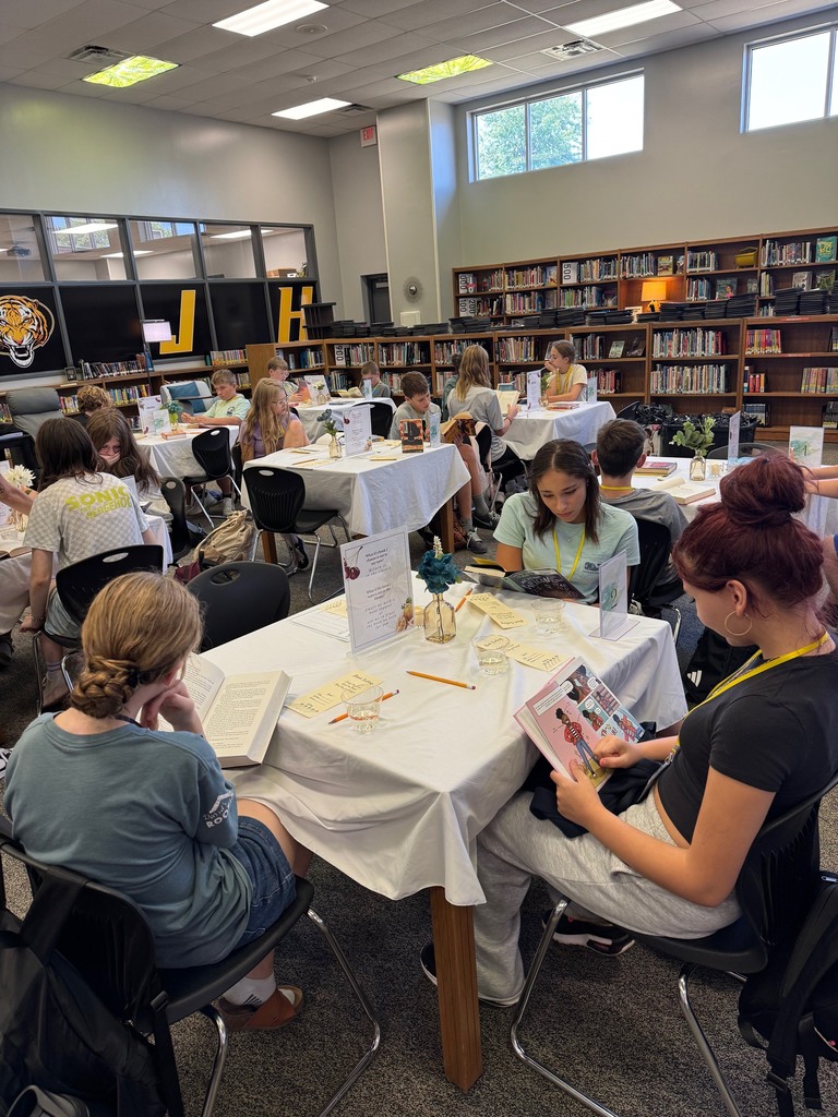 Students in the library browse books at tables.