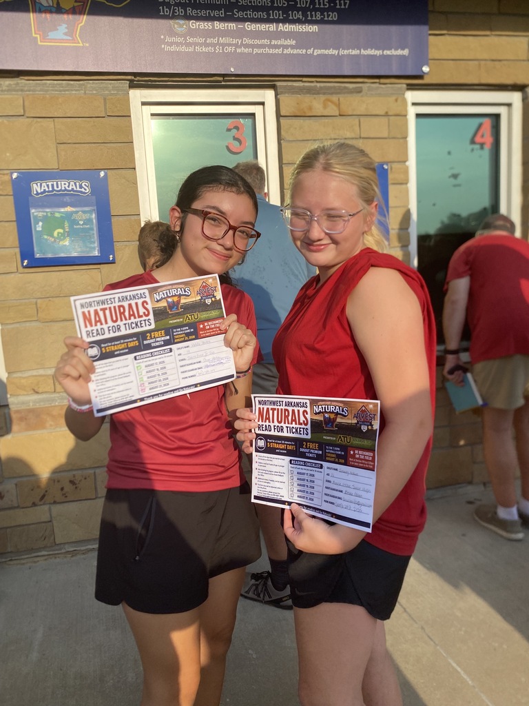 Two students hold "Read for Tickets" signs at the Naturals game.