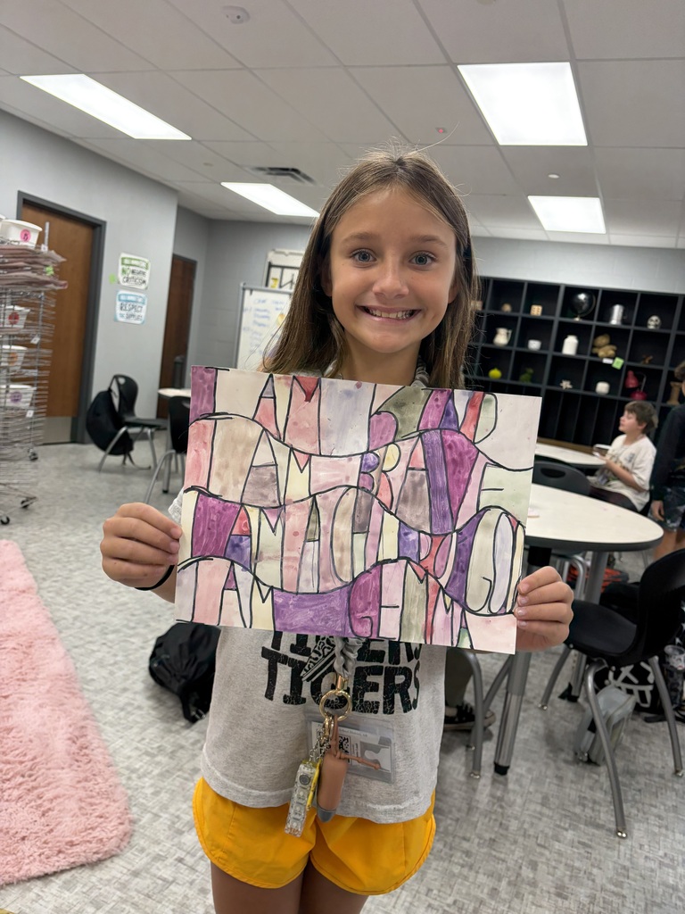 A student shows off her art work in an art classroom
