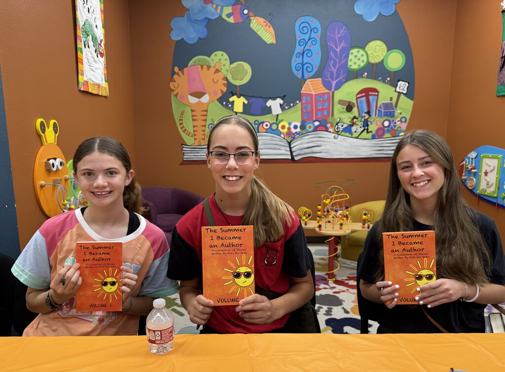 Three young authors pose with their published collection of short stories