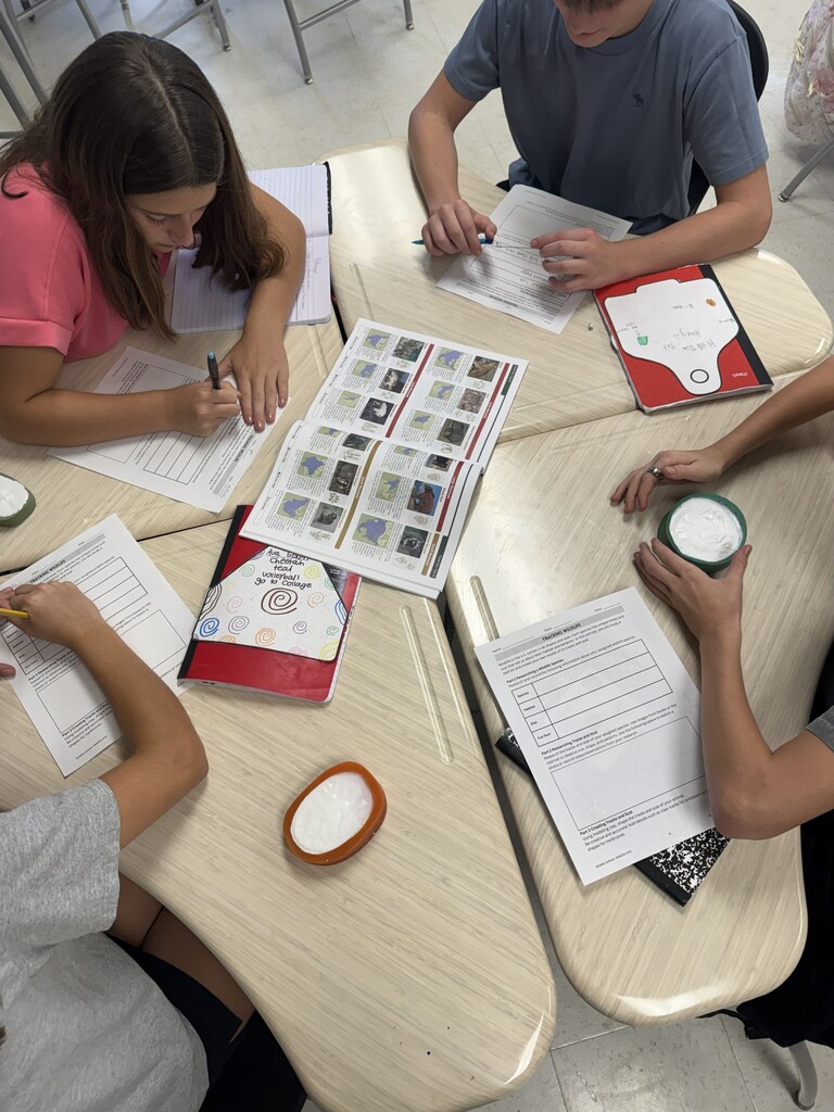 Students study animal tracks at a table