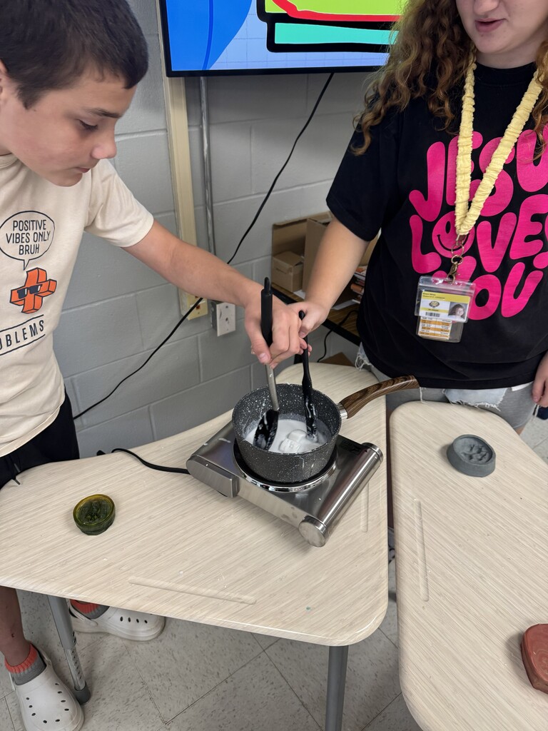 Students melt soap at a table with animal track molds