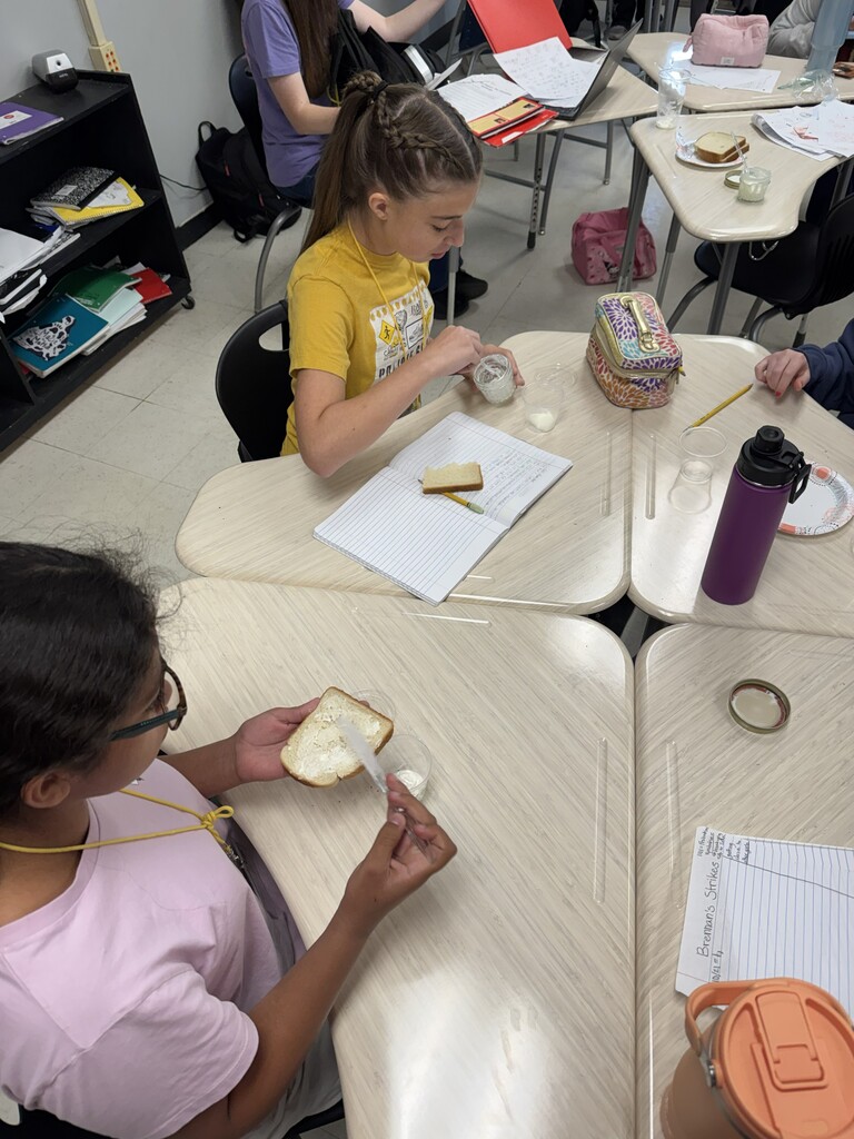 Students at tables spread butter on bread