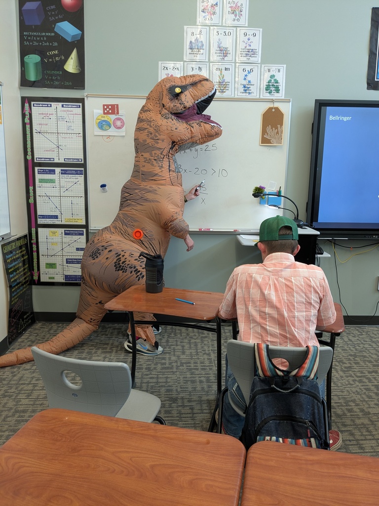 person in dinosaur costume stands at white board in math class