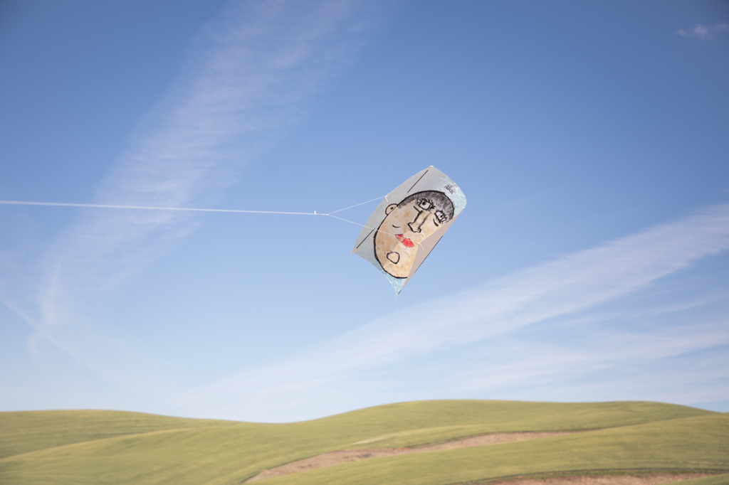 Self Portrait kite flies in the blue sky with the Prescott rolling hills in the background
