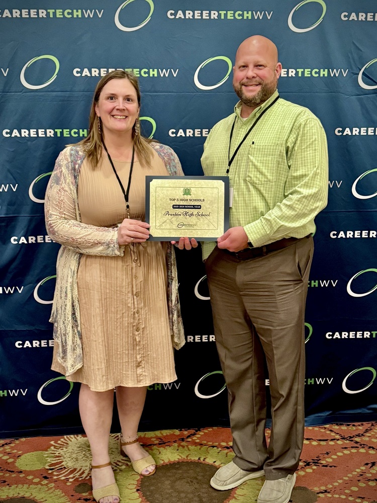 male and female educator pose with a n award