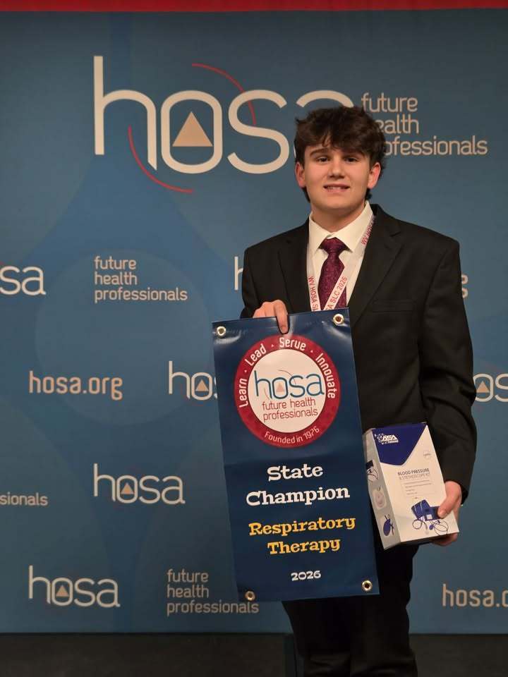 student poses with award