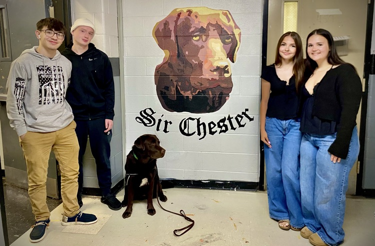 students and dog in front of mural