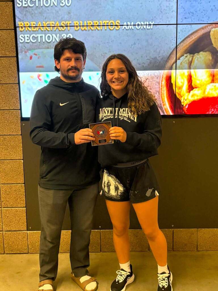 female wrestler poses with coach with award