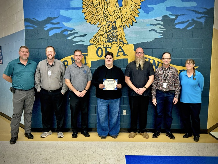 parent poses with board members at a meeting for recognition