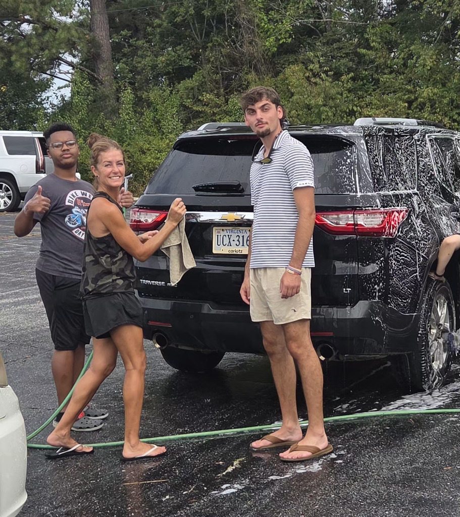 people posing in front of black car