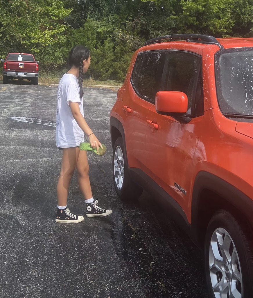 girl washing orange SUV